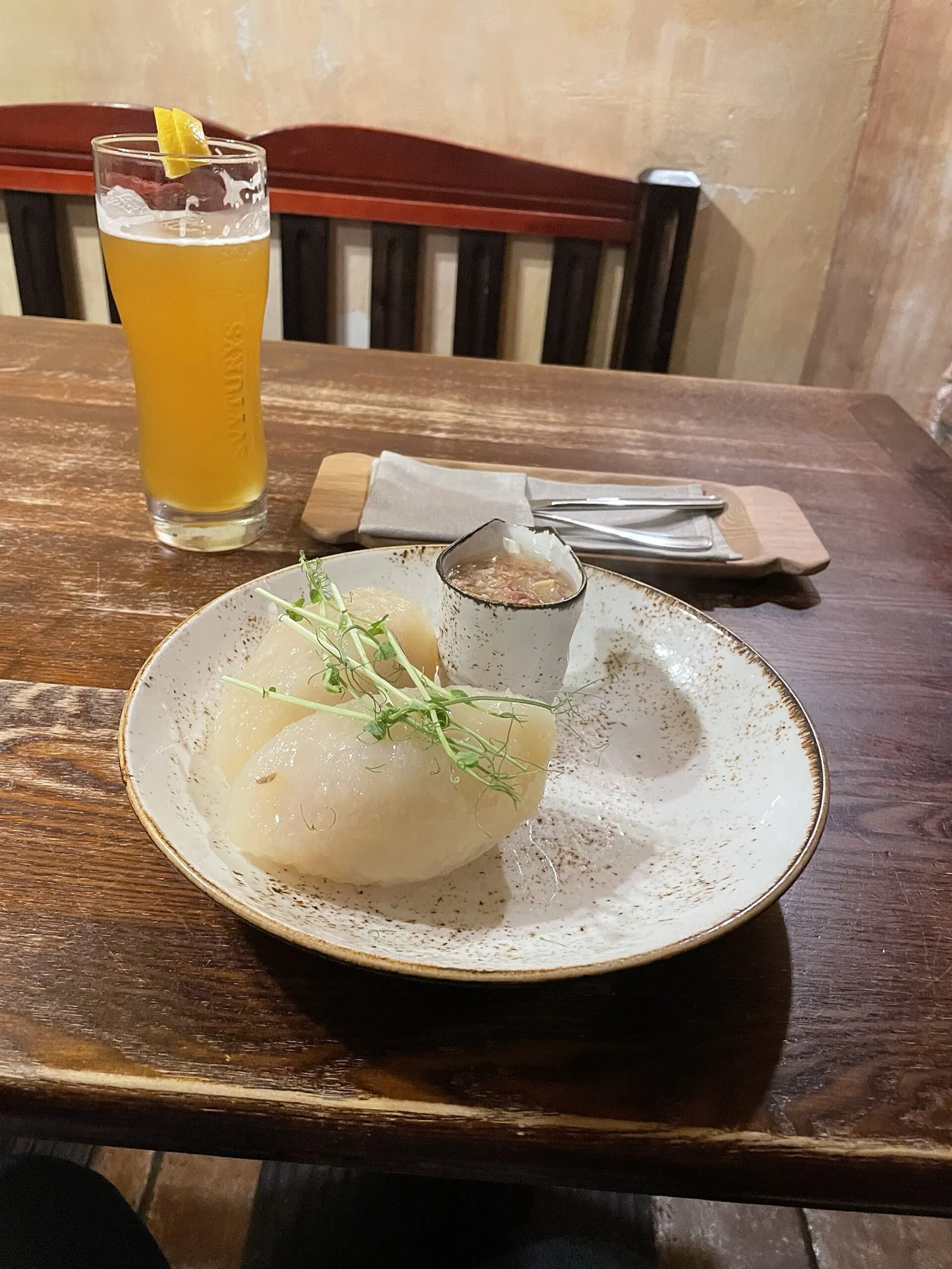 A plate of cepelinai — zeppelin-shaped potato dumplings — served with a glass of Lithuanian beer